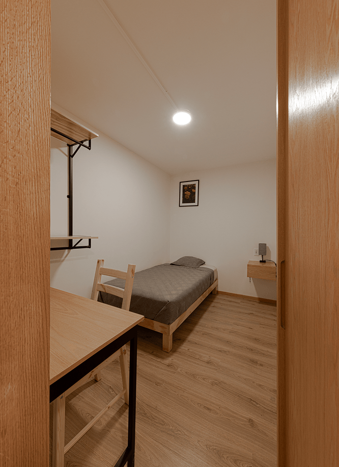 Habitación sencilla en coliving Roma Norte con cama individual y mobiliario básico